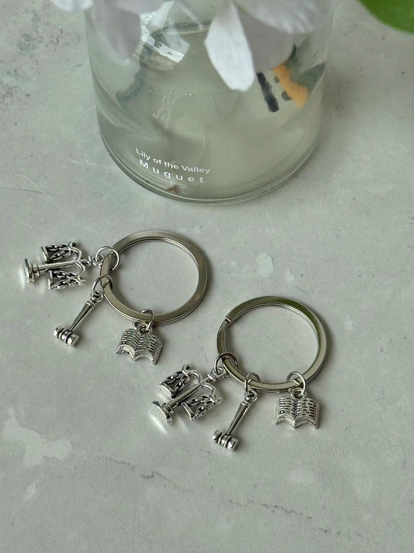 Lawyer Keychain — A premium silver keychain featuring three iconic legal charms — the scales of justice, a gavel, and a law book. The perfect add-on gift for any lawyer or law graduate.